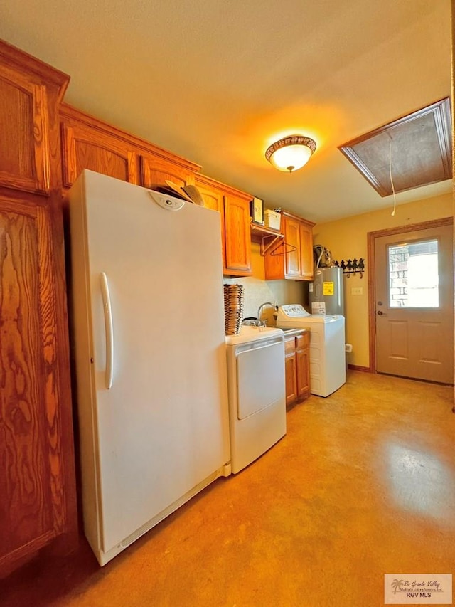 kitchen with white fridge, washer / dryer, and electric water heater