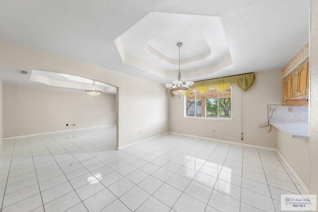 interior space with a textured ceiling, a tray ceiling, and a notable chandelier