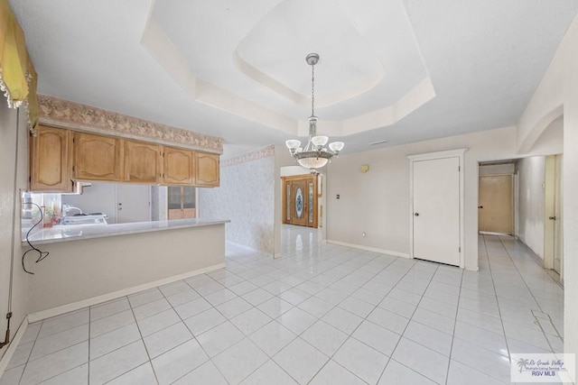 kitchen with pendant lighting, an inviting chandelier, a raised ceiling, light tile patterned flooring, and kitchen peninsula