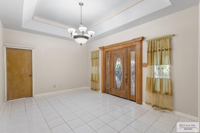 tiled foyer entrance with a raised ceiling and a chandelier