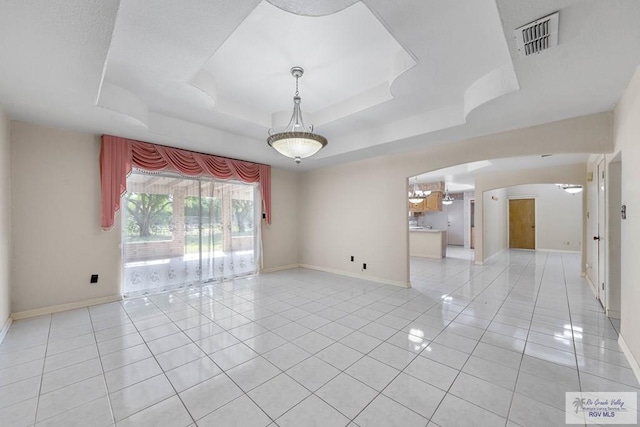 empty room featuring a raised ceiling and light tile patterned floors