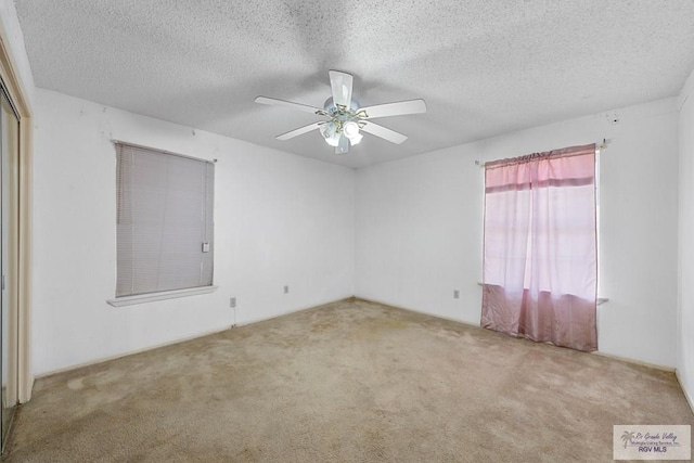 carpeted empty room featuring ceiling fan and a textured ceiling