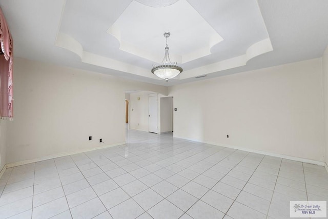 spare room with a tray ceiling and light tile patterned floors