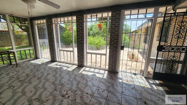 unfurnished sunroom with ceiling fan and a healthy amount of sunlight