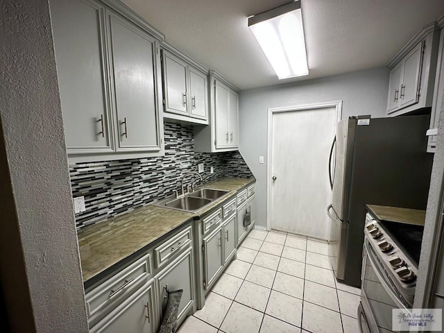 kitchen with gray cabinets, a sink, tasteful backsplash, stainless steel appliances, and light tile patterned flooring