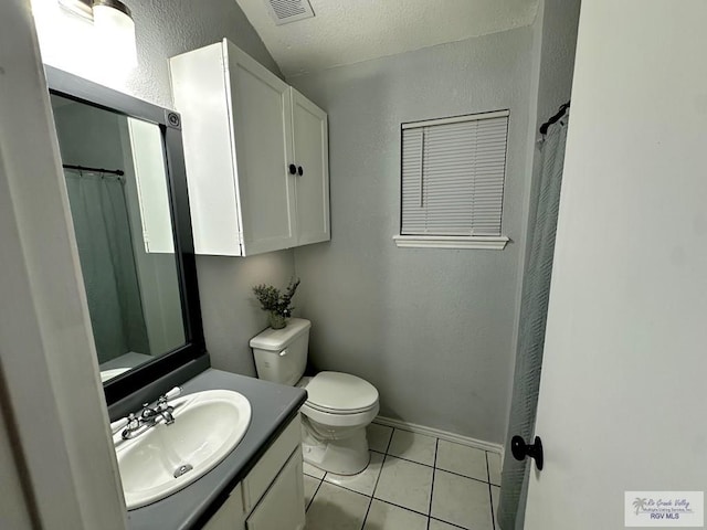 bathroom featuring vanity, visible vents, tile patterned floors, toilet, and a textured wall