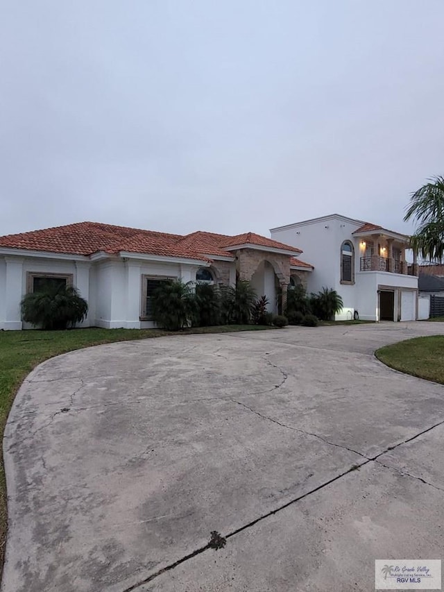 view of front of house featuring a garage, a balcony, and a front yard