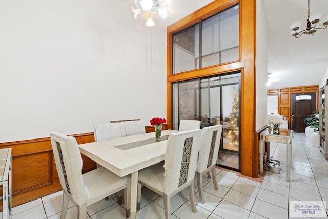 dining room featuring a chandelier, wood walls, and light tile patterned flooring