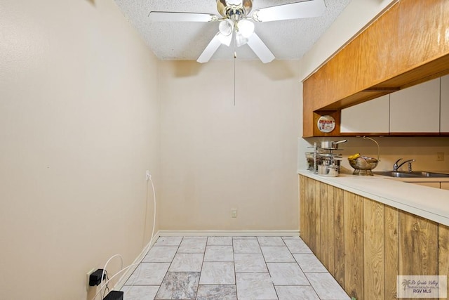 kitchen with ceiling fan, sink, light tile patterned floors, and a textured ceiling