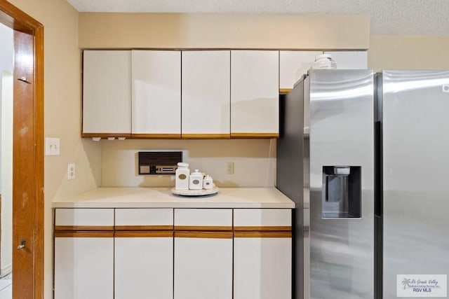 kitchen featuring white cabinetry, stainless steel fridge, and a textured ceiling