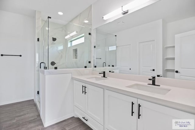 full bathroom with double vanity, wood finished floors, a stall shower, and a sink