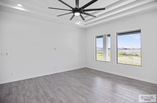 spare room with ceiling fan, wood finished floors, and baseboards