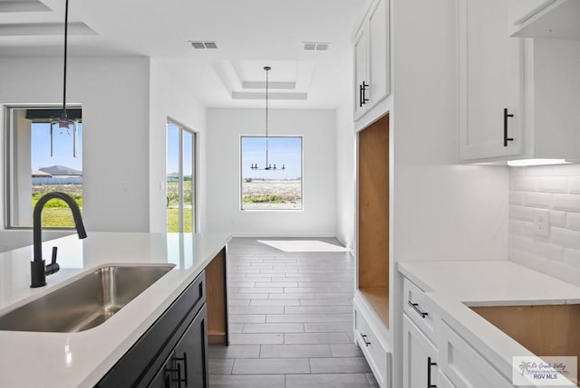 kitchen featuring light countertops, a raised ceiling, visible vents, and a sink