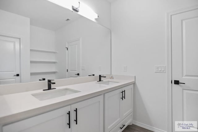 full bath with double vanity, a sink, and baseboards