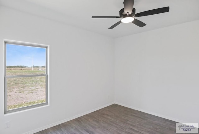 unfurnished room with a ceiling fan, baseboards, and dark wood-type flooring