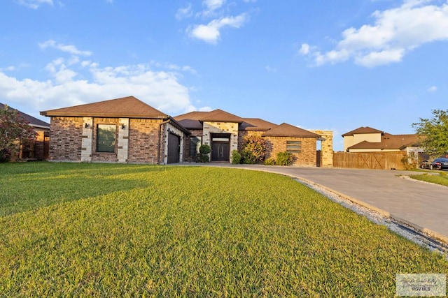 prairie-style house featuring driveway, an attached garage, a front yard, brick siding, and fence