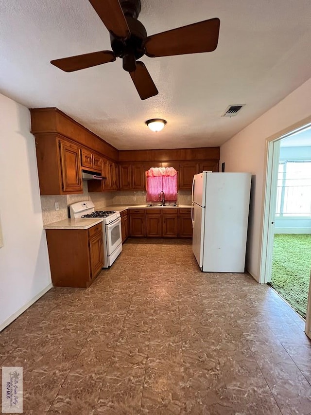 kitchen with backsplash, a textured ceiling, white appliances, ceiling fan, and sink