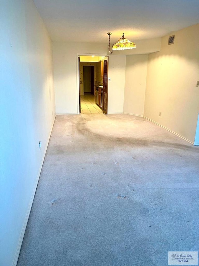 spare room featuring light carpet, baseboards, and visible vents