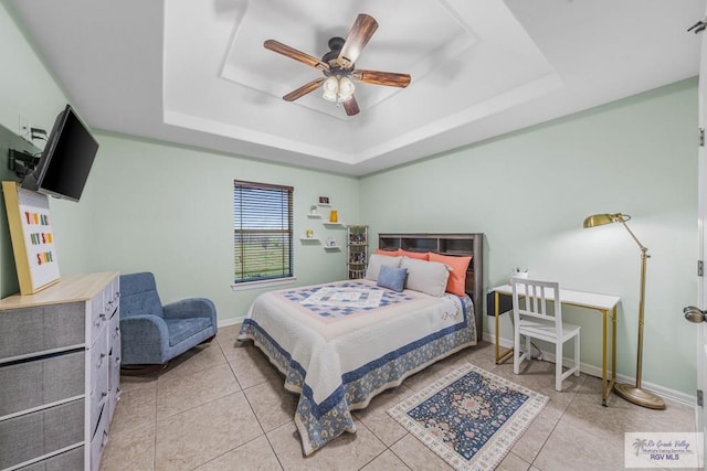 tiled bedroom featuring ceiling fan and a tray ceiling