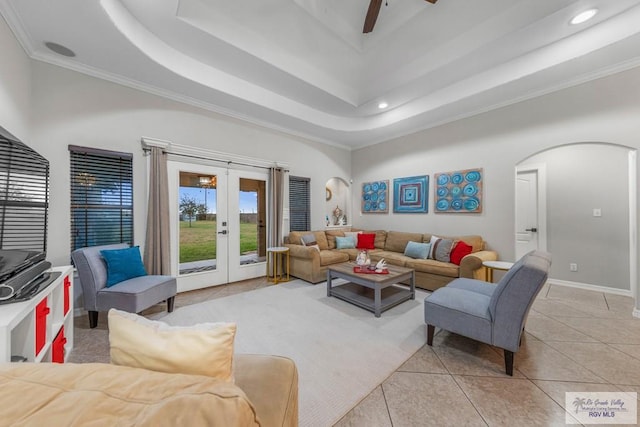 tiled living room with french doors, ceiling fan, a raised ceiling, and a towering ceiling