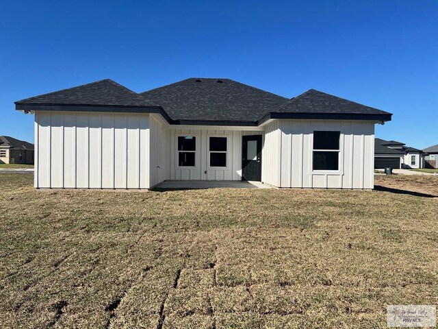 8713 Swan Lake Dr, Harlingen, TX 78552 - rear view of house with board and batten siding, a shingled roof, and a yard