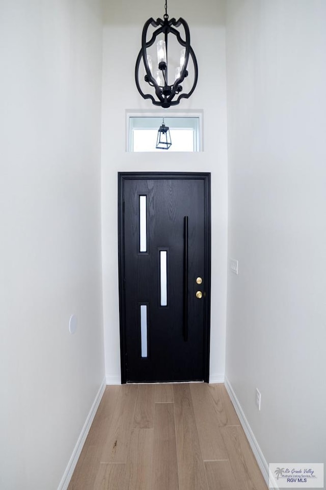8713 Swan Lake Dr, Harlingen, TX 78552 - foyer featuring baseboards, light wood finished floors, and a chandelier