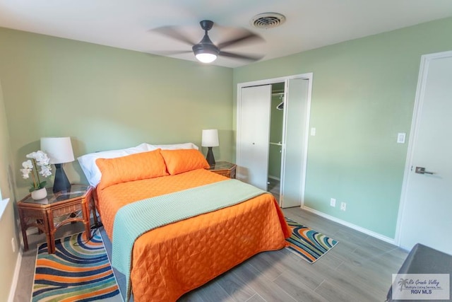 bedroom featuring hardwood / wood-style flooring, ceiling fan, and a closet