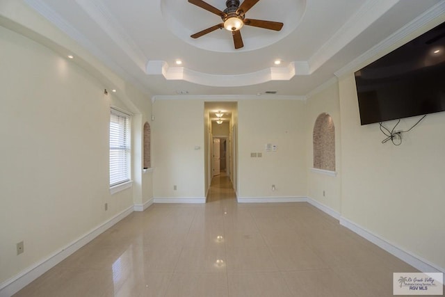 tiled empty room with ceiling fan, ornamental molding, and a tray ceiling