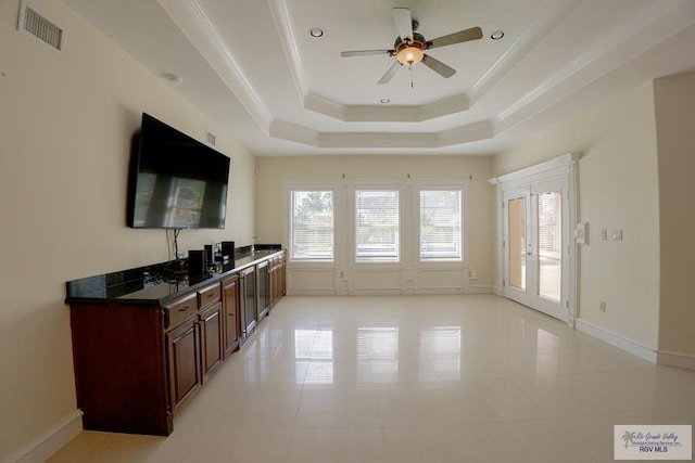 kitchen with light tile patterned floors, a raised ceiling, ceiling fan, and ornamental molding