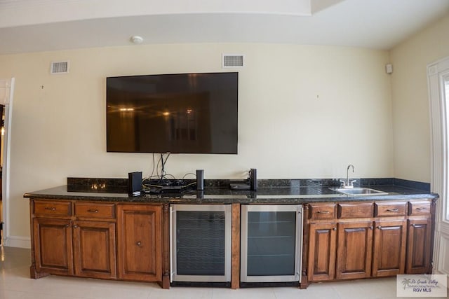 kitchen featuring wine cooler, sink, light tile patterned floors, and dark stone countertops