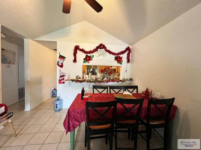 dining space featuring vaulted ceiling, ceiling fan, tile patterned floors, and a textured ceiling