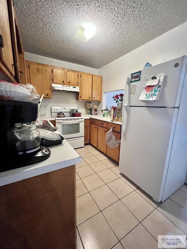 kitchen featuring light tile patterned flooring, white appliances, and a textured ceiling