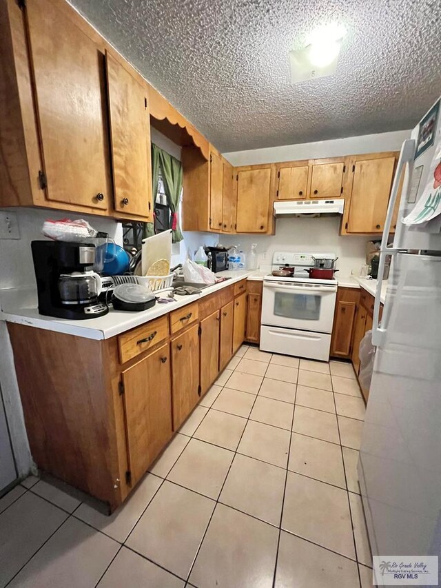 kitchen with light tile patterned floors, white appliances, and a textured ceiling