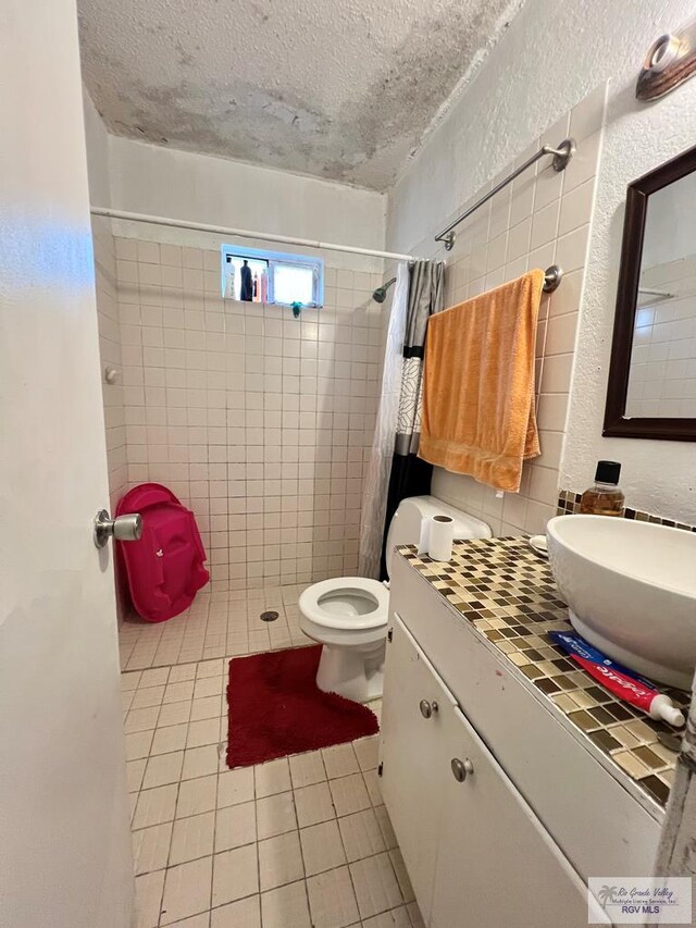 bathroom with tile patterned floors, toilet, a textured ceiling, curtained shower, and backsplash