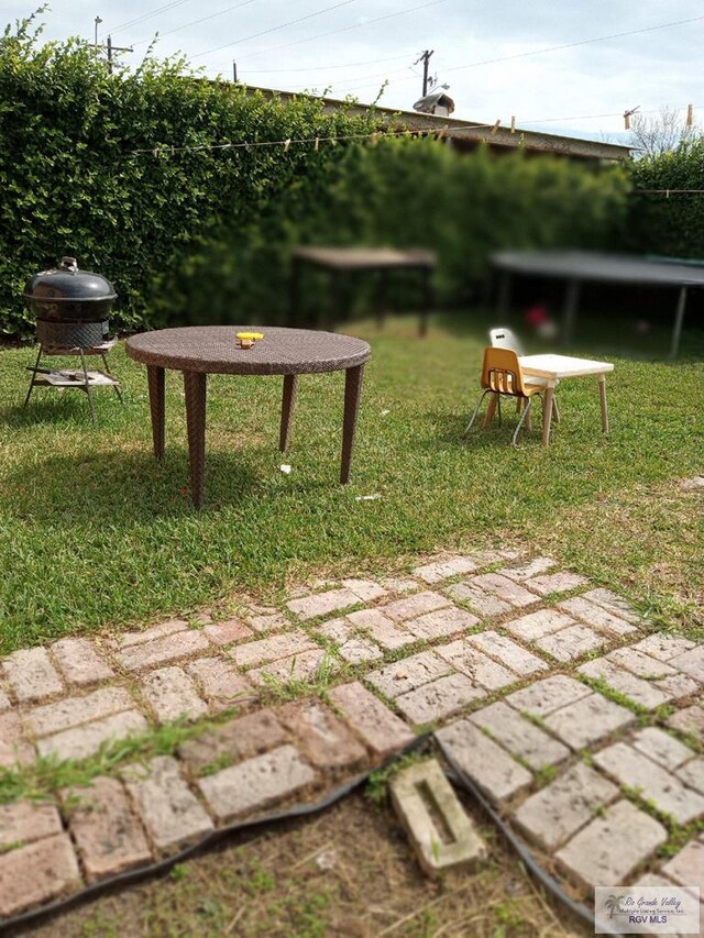 view of property's community with a trampoline and a lawn