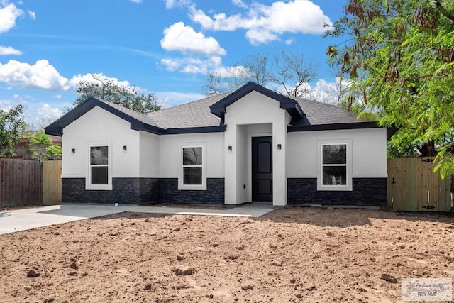 ranch-style house featuring stone siding, stucco siding, a patio, and fence