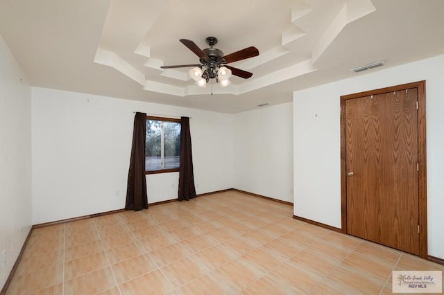 unfurnished room with ceiling fan and a tray ceiling