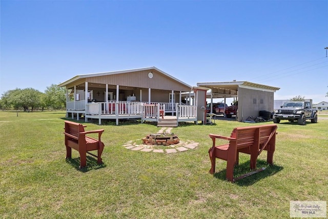 30202 Ratliff Rd, San Benito, TX 78586 - rear view of house with an outdoor fire pit, a carport, a wooden deck, and a lawn