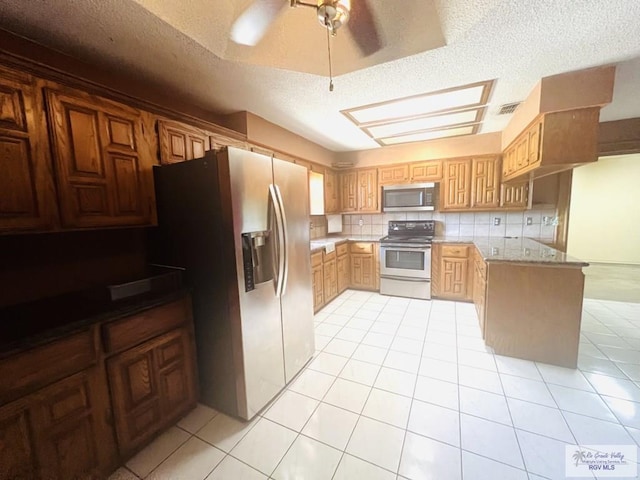 4407 Alejandro St, Mission, TX 78573 - kitchen with stainless steel appliances, a textured ceiling, light tile patterned floors, backsplash, and a peninsula