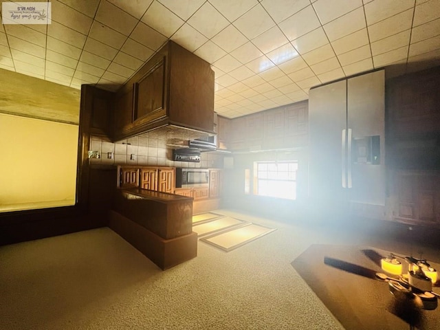 4407 Alejandro St, Mission, TX 78573 - kitchen with carpet flooring, stainless steel microwave, backsplash, and dark brown cabinets
