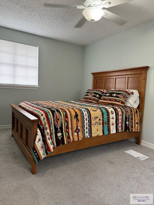 bedroom with a textured ceiling, ceiling fan, and light carpet