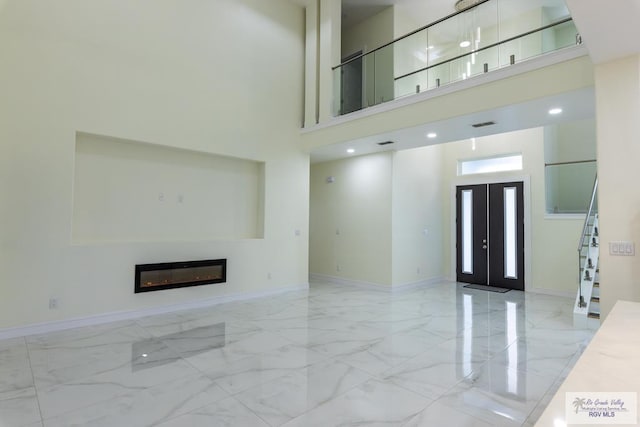 unfurnished living room featuring french doors and a high ceiling