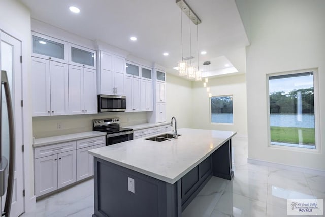 kitchen featuring sink, white cabinetry, a center island with sink, pendant lighting, and stainless steel appliances