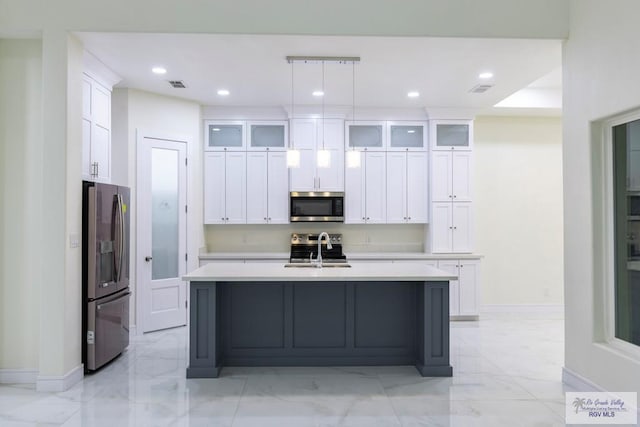 kitchen with appliances with stainless steel finishes, sink, a center island with sink, and decorative light fixtures