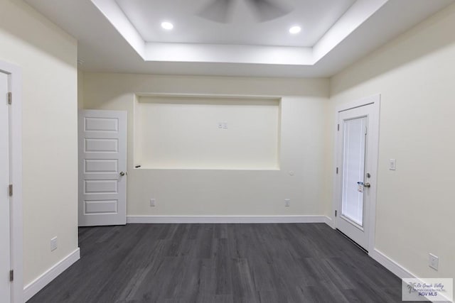 spare room with dark hardwood / wood-style floors and a raised ceiling