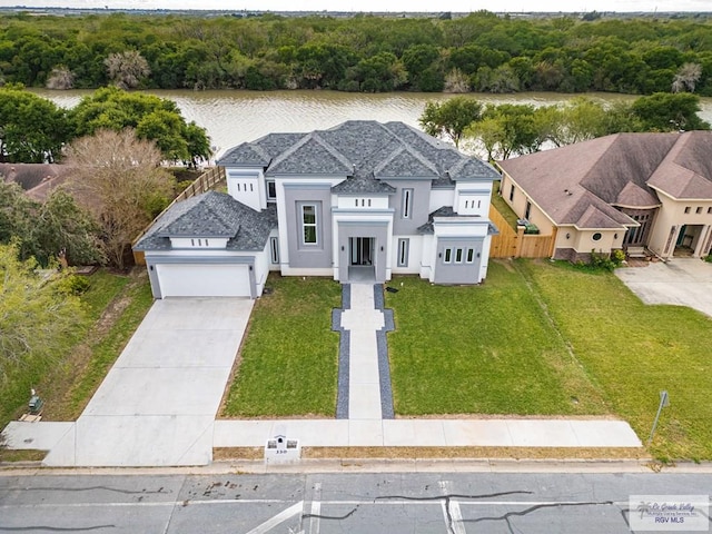 view of front of house featuring a garage, a front lawn, and a water view