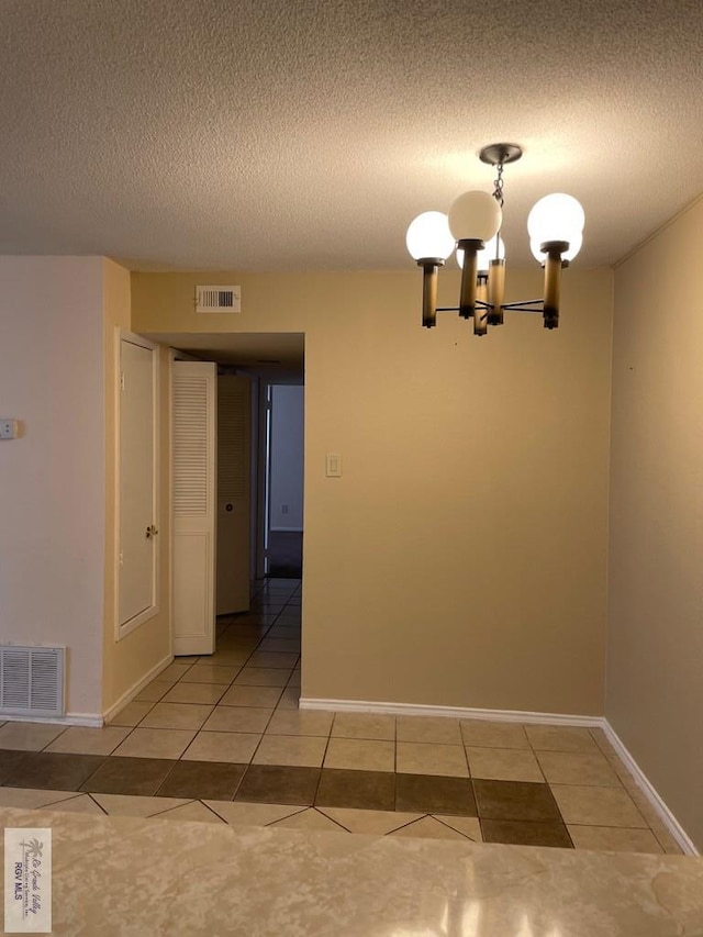 unfurnished dining area featuring light tile patterned flooring, a textured ceiling, and an inviting chandelier