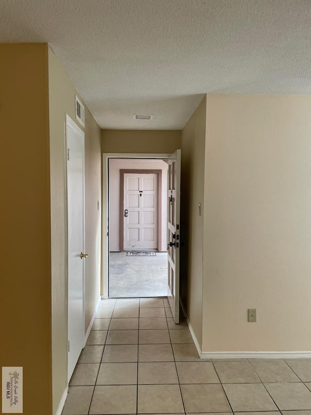 hallway featuring light tile patterned floors and a textured ceiling