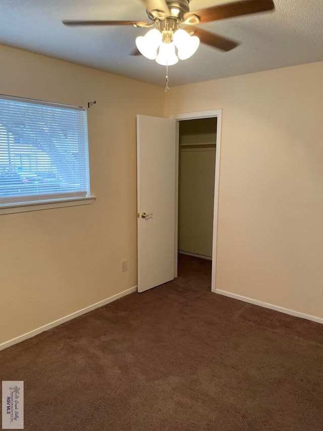 unfurnished bedroom featuring ceiling fan, a closet, and dark colored carpet