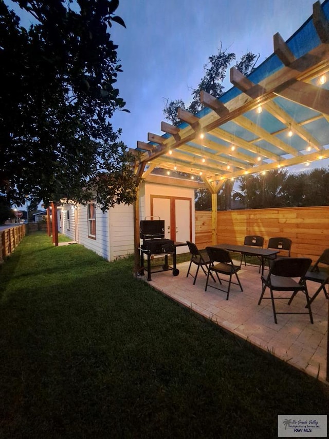 patio terrace at dusk with a pergola and a yard